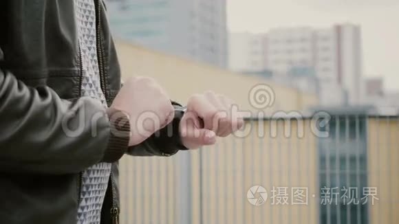 男人用他的智能手表触摸屏站在屋顶上，然后走开。 双手特写。 4k