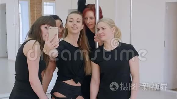 一群漂亮的年轻女性在钢管舞课上用智能手机自拍