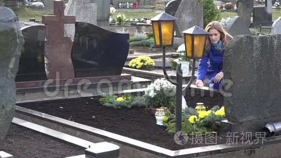 伤心的女人在里把蜡烛放在爱父兄弟的坟墓上。 4K