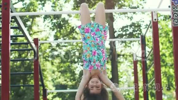 小有趣的女孩倒挂在水平杆上。