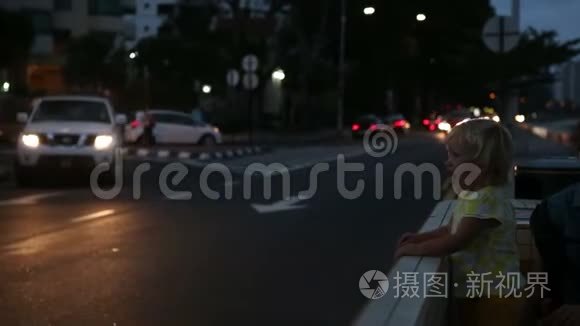 女儿和母亲坐在靠近城市道路的长凳上