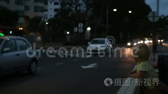 女儿和母亲坐在靠近城市道路的长凳上