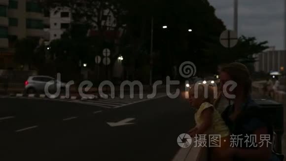 女儿和母亲坐在靠近城市道路的长凳上