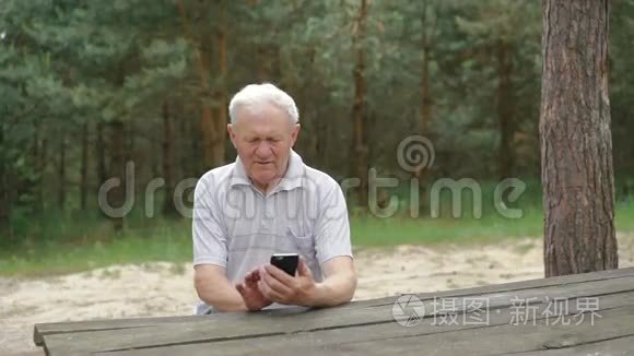 这位老人在森林的餐桌上用电话视频