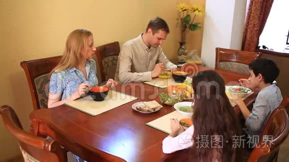 一家人在家里的餐厅用餐。 青少年、双胞胎及其父母