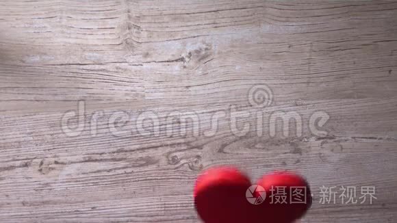 女孩把两颗红心放在一张木桌上，俯视。 约会，爱情，家庭观念.. 4K视频