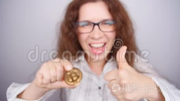 幸福的女人拿着一个黄金比特币视频