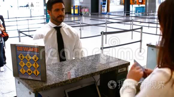 两名女机场工作人员在登记台检查护照并与通勤者互动