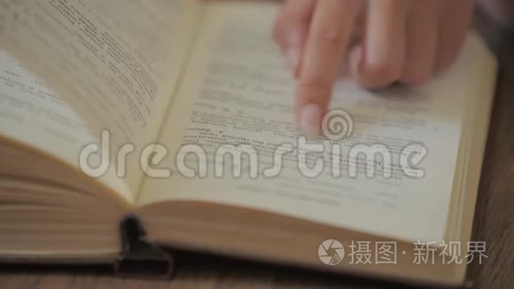 女人的手拿着一本书，在阅读教育休闲读物时，手指在书页上移动