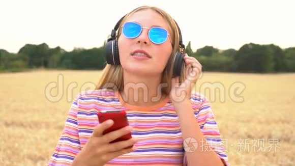 年轻女子戴着蓝色太阳镜在野外听无线耳机音乐