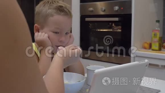 妈妈一边喂孩子一边看平板电脑视频