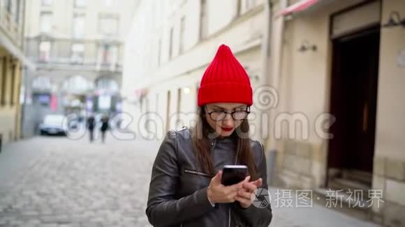 嘴唇红的女人在智能手机上说话，沿着中世纪的街道漫步