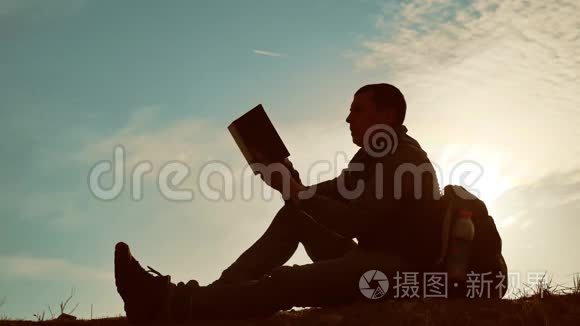 男学生在公园里背着背包看日落。 生活方式天空夕阳下男子读书剪影