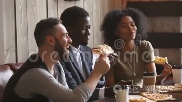 多种族快乐的年轻人在披萨店开会时吃披萨