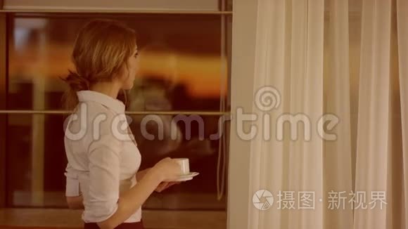 年轻女子站在窗前喝杯茶或咖啡视频