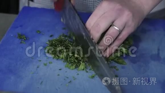 厨师`双手剁碎的绿色食品在一个商业厨房的板上装饰