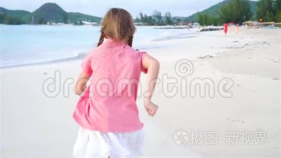 可爱的小女孩在海滩上奔跑。 快乐的孩子享受暑假。 慢动作