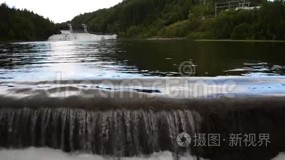 银河白河洪水在夏季阳光下越过混凝土屏障，背景是水力发电厂