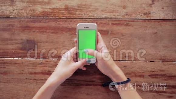 女士使用智能手机，木制桌子背景上有绿色屏幕
