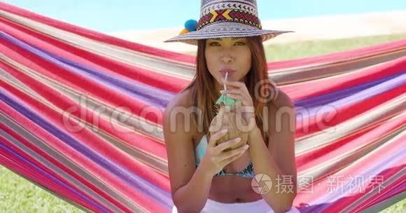 有椰子饮料的女人坐在吊床上视频