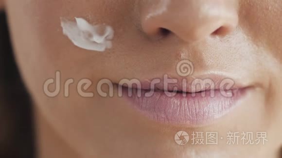 幸福微笑的美丽年轻女子的肖像，触摸皮肤或涂抹奶油，淋浴后头上戴毛巾