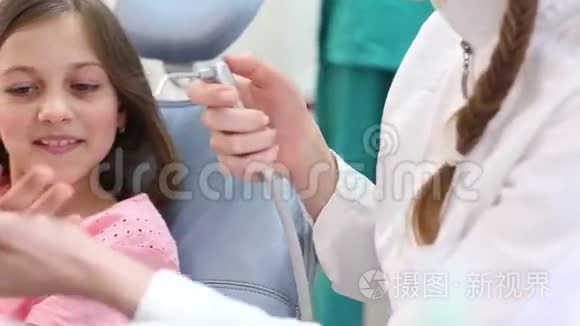 女牙医给小女孩看牙科器械视频