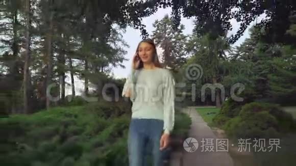 一个年轻的女孩正在瘦公园里打电话，微笑着，惊讶着。