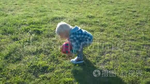 一个半岁的男孩高兴地在球场上追逐球