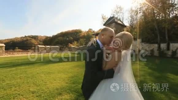 新婚快乐的新婚夫妇在中世纪城堡的院子里温柔地接吻