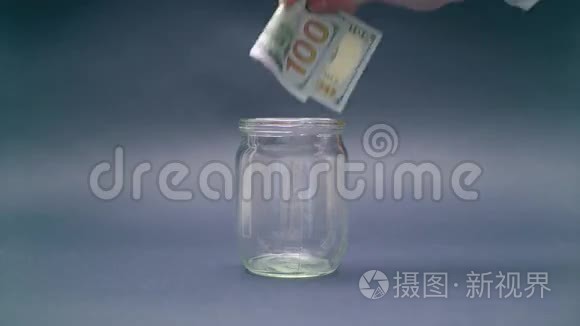 女人把100美元放进玻璃罐