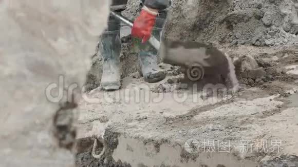 在建筑工地用铲子收集水泥的胶靴工人