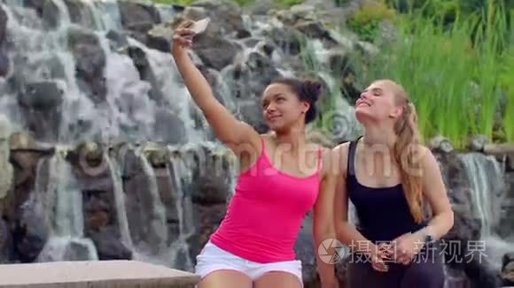 自私的女人。 两个年轻女人在瀑布附近自拍。 女人自拍