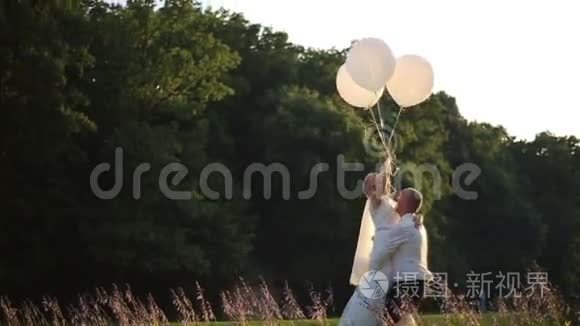 性感的爱情时刻。 快乐的新郎手里拿着气球的新娘。 阳光夏日田野背景