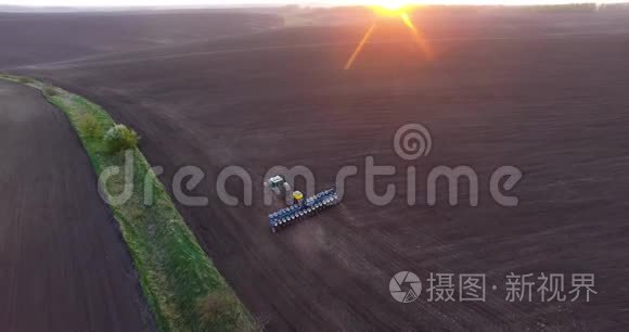 日落时种植小麦的拖拉机的俯视图