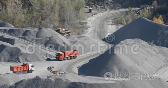 自卸卡车在花岗岩采石场行驶，在采石场用重型机械开采石块