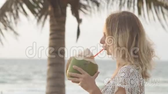 日落时分在海滩上喝椰子的女人视频