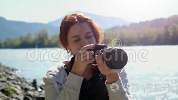 美丽的女人与红色头发摄影师拍照使用专业相机户外远足。 女性徒步旅行者