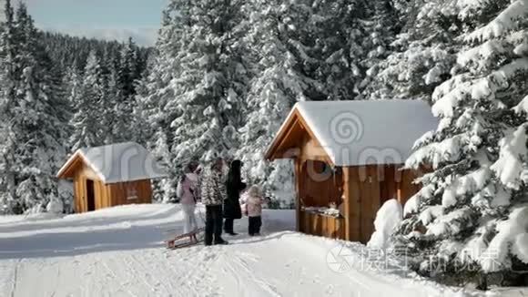 带雪橇的家庭参观小木屋