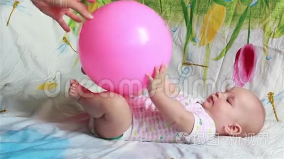 可爱的宝宝躺在床上玩一个红色的大球