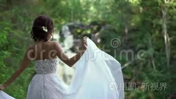 新娘在瀑布附近盘旋挥舞着礼服视频