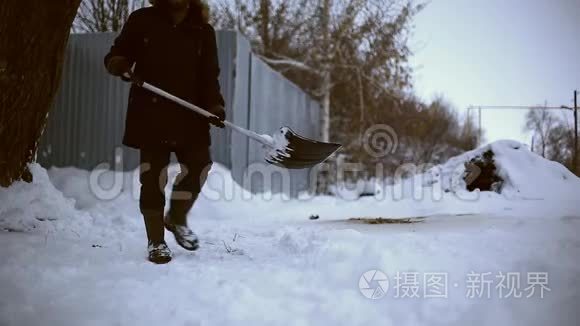 雪夜后工作.. 在一个寒冷的雪天早晨，一个拿着铲子把雪从他的院子里移走的人。