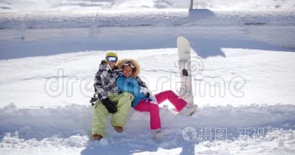 幸福的年轻夫妇坐在厚厚的雪架上