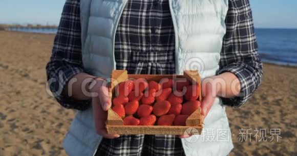 女人手里拿着装满成熟草莓的木箱