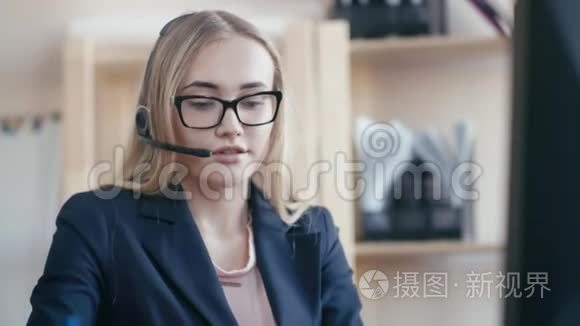 呼叫中心员工在办公室工作。 一个金发女孩戴着眼镜坐在办公室的桌子旁