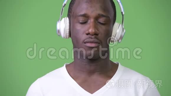 非洲年轻人在绿色背景下听音乐视频