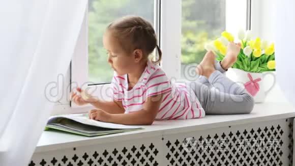 特写小可爱女孩在家窗台上看书的画像..
