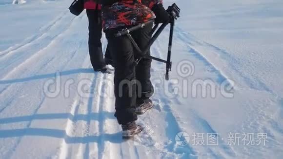 团队合作。 男游客摄影师冬天乘三脚架爬山顶山顶山顶群去下雪