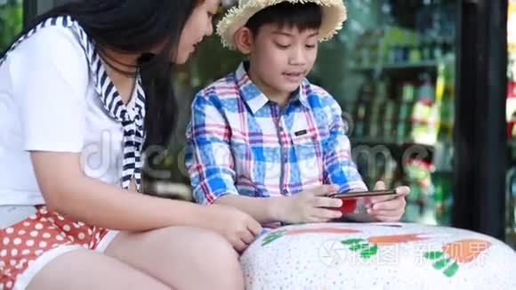 带着手机的小亚洲男孩和十几岁的女孩一起聊天