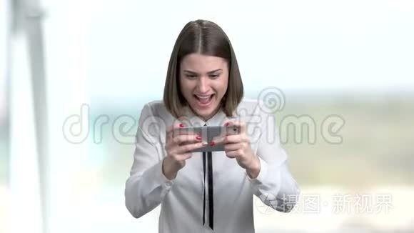 年轻有趣的女人在智能手机上玩游戏。
