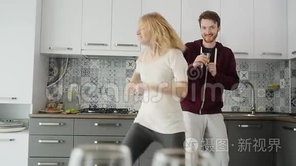 早上在家幸福的年轻夫妇新婚夫妇在厨房里听音乐跳舞